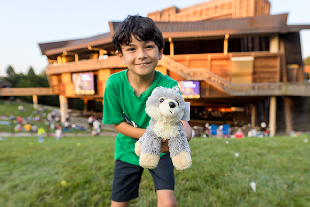 Child holds a Wolfie toy at the Filene Center.
