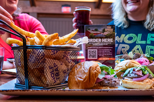 Lamb sliders and fries enjoyed by smiling patrons.