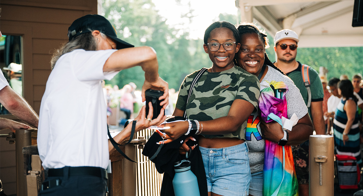 Smiling mother and daughter scan their Wolf Trap tickets at the front gate.