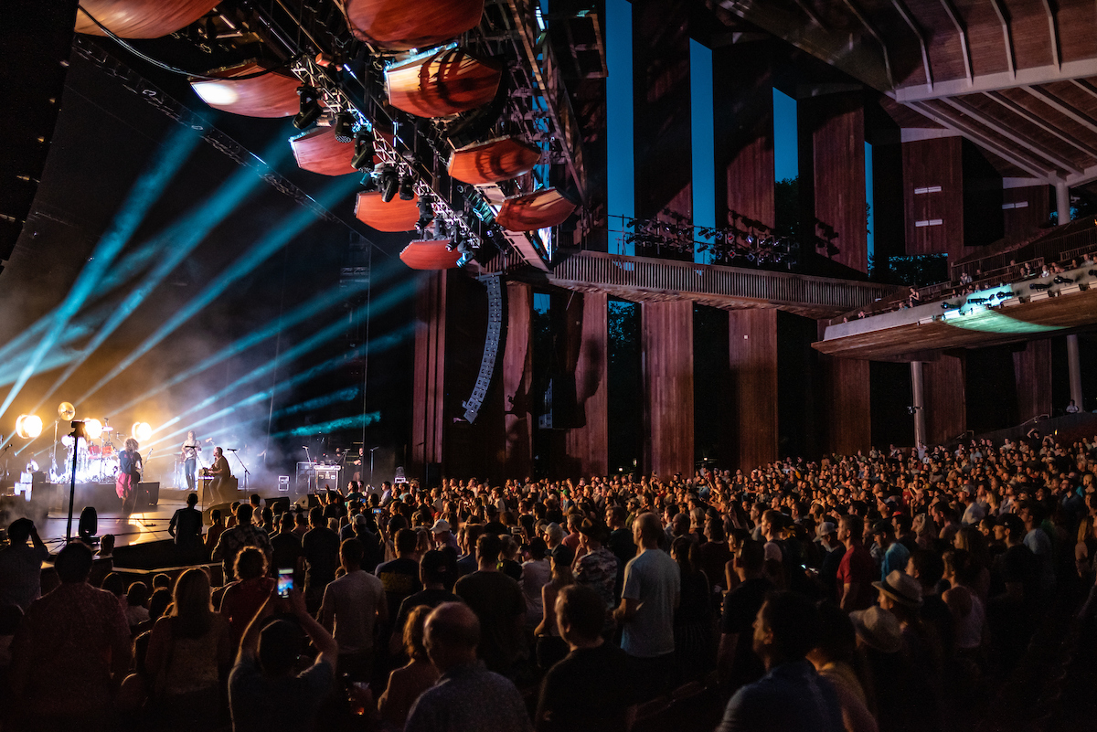 Performance at the Filene Center stage with beams of light shining on the performers.