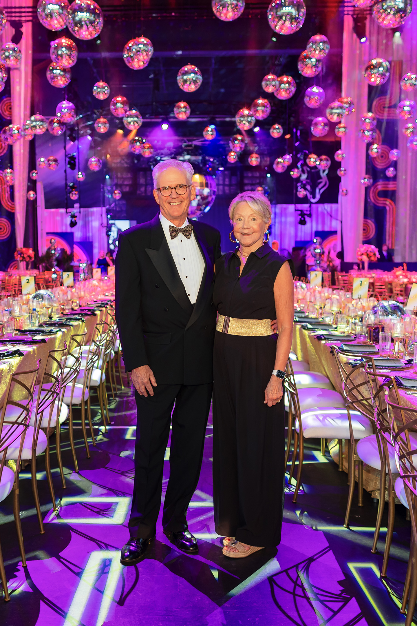 Board Members in black tie attire pose under an array of disco balls.