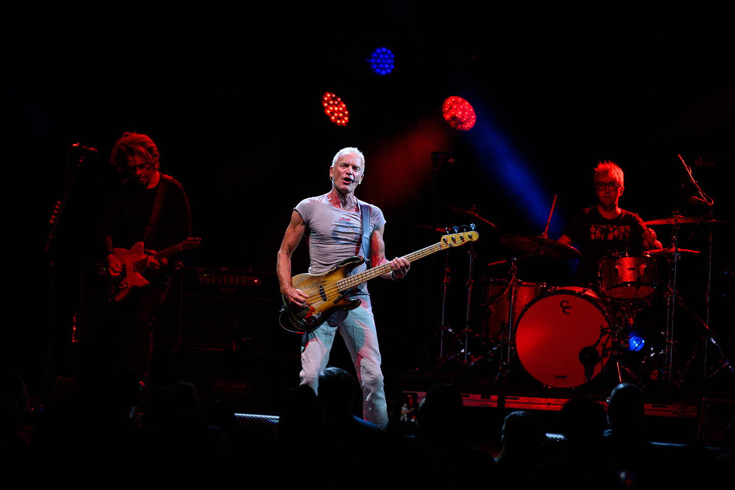 Sting plays his guitar and sings on the Filene Center stage, surrounded by red and blue lights.