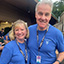 Volunteers Jim and Stacy Riordan pose in front of the Wolf Trap Gift Shop wearing their blue volunteer polos.