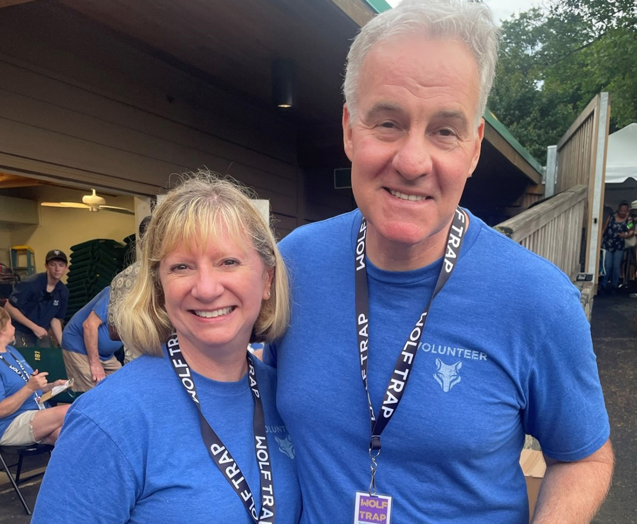 Volunteers Jim and Stacy Riordan pose in front of the Wolf Trap Gift Shop wearing their blue volunteer polos.