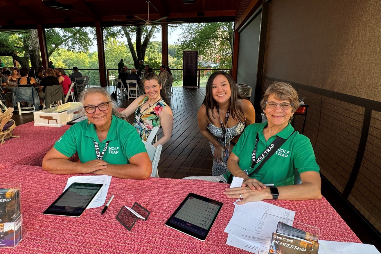 Two volunteers and two staff members at a member event registration table.