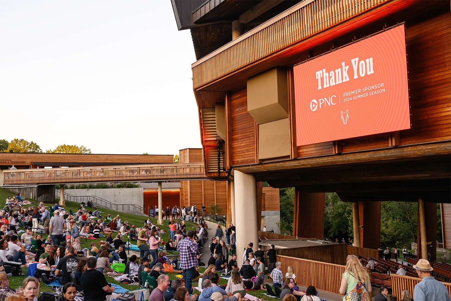 Patrons on the Lawn before a concert, with "Thank You PNC" displayed on a screen.