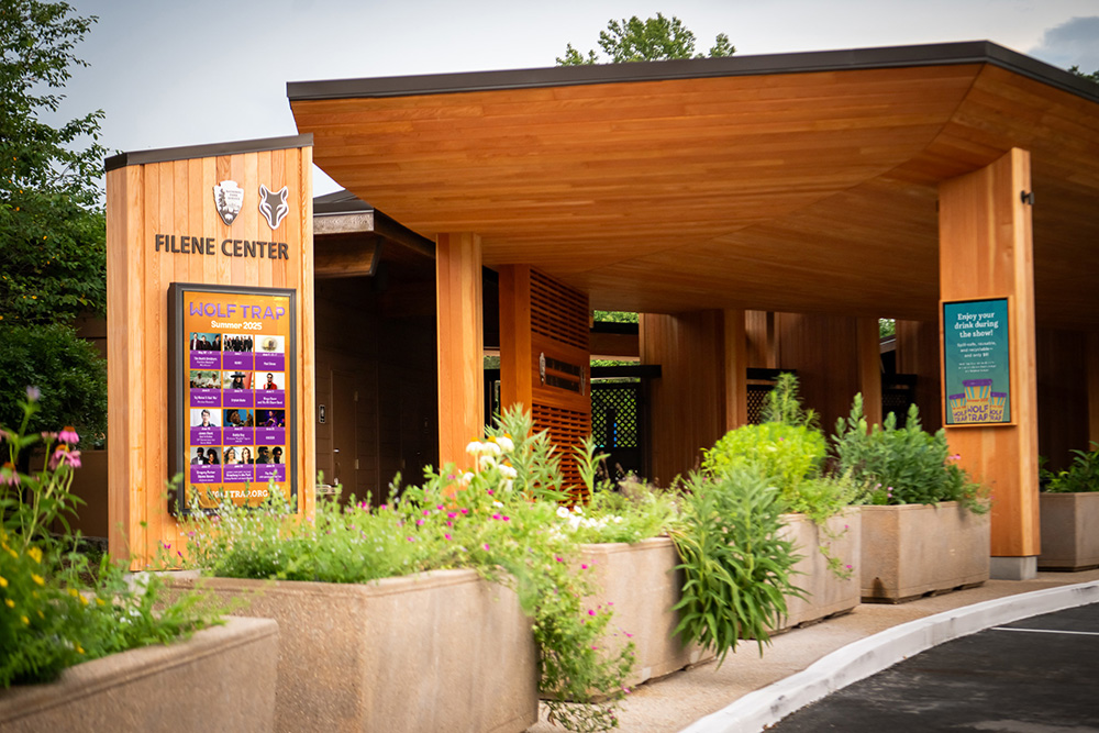 A closeup of the entrance to Wolf Trap's new main gate, surrounded by greenery and with colorful posters on the display screens.