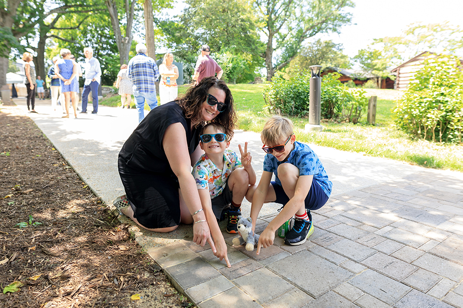 Family wearing sunglasses point to the Meadow Overlook paver with their names on it.