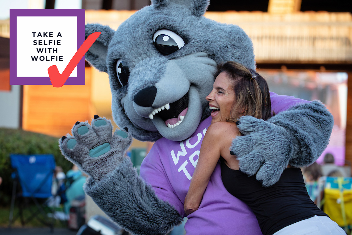 Bingo card item "Take a Selfie with Wolfie" checked off, next to a photo of a woman hugging wolfie.